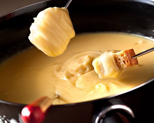 Queso fundido siendo servido desde una sartén caliente